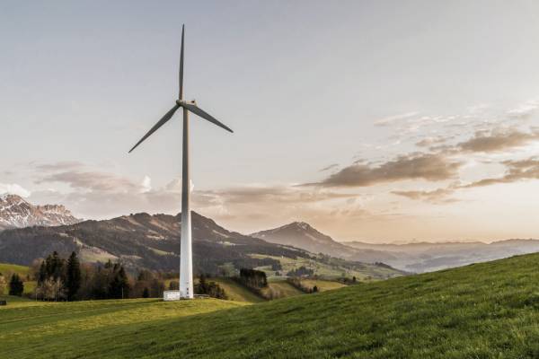 Windenergie und nachhaltige Energietechnik Windturbine auf einem Hügel bei Sonnenuntergang, repräsentiert nachhaltige Energietechniklösungen.